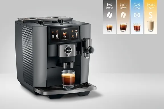 Dunkelgrauer Jura J10 twin Kaffeevollautomat mit zwei Bohnenbehältern, großem Display und einem Glas Kaffee.