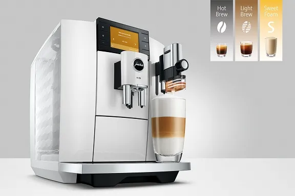 Weißer Jura E8 Kaffeevollautomat mit Farbdisplay bereitet einen Latte macchiato in einem hohen Glas zu.